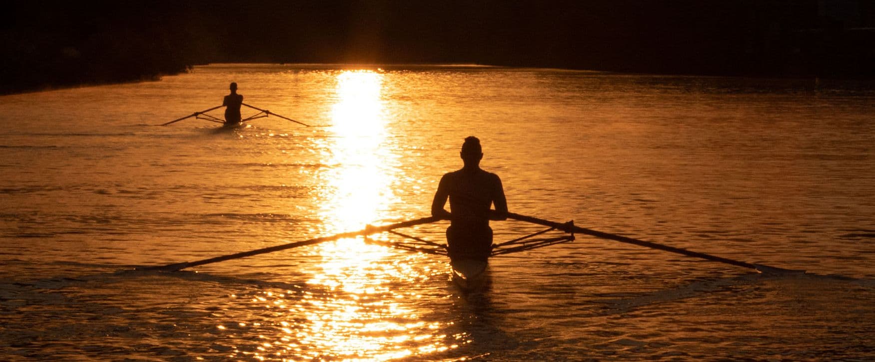 Zwei Ruderer rudern im Sonnenuntergang auf dem Wasser