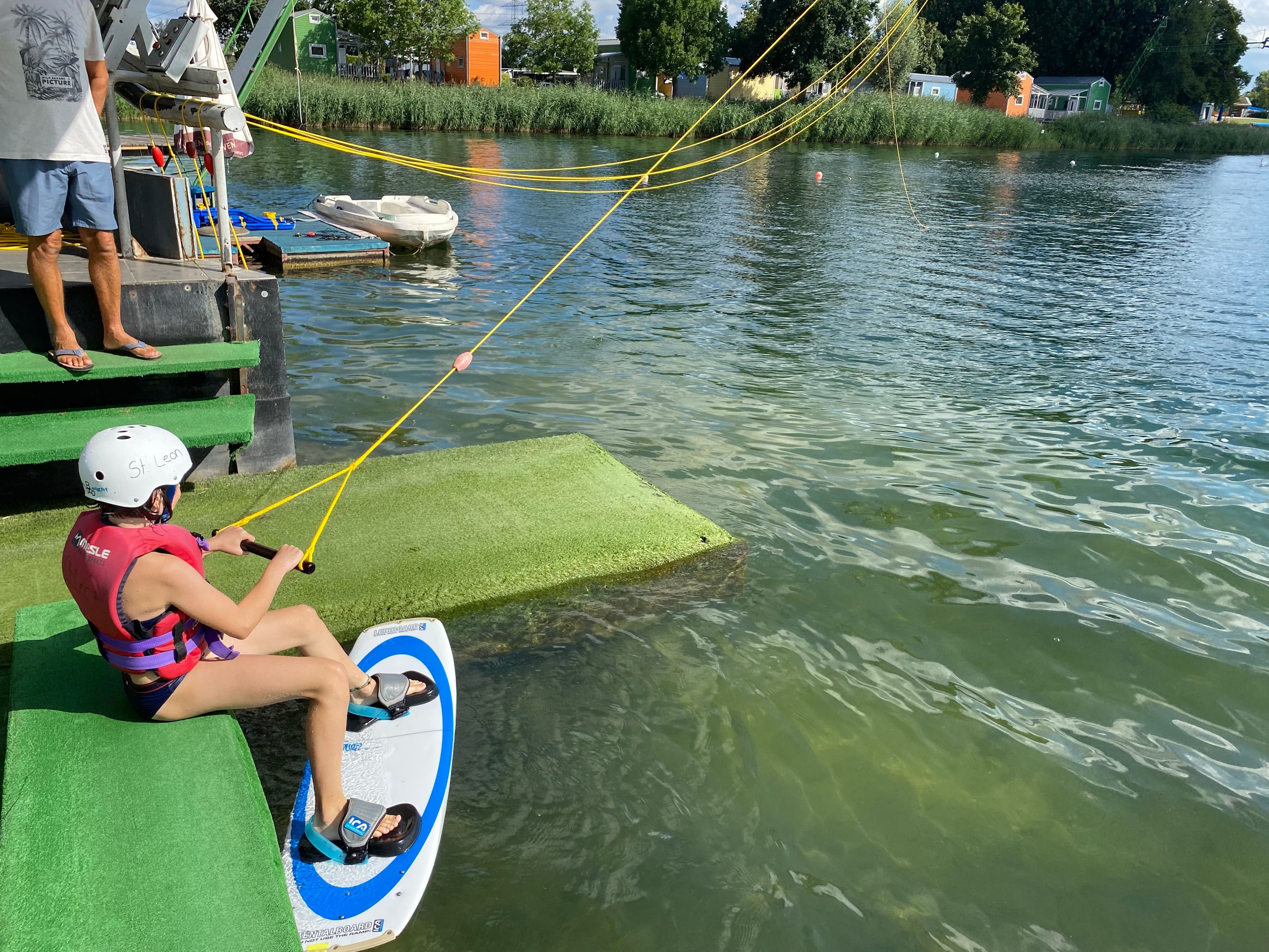 Eine Person sitzt am Start einer Wakeboardanlage